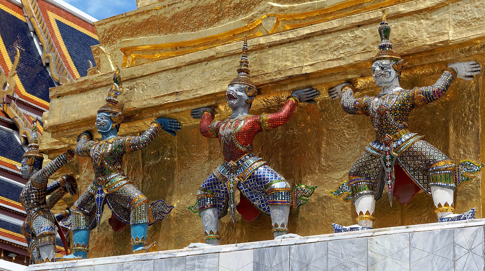 Gilded and mirror-mosaic yaksha guardian statues supporting a golden chedi within the Grand Palace complex
