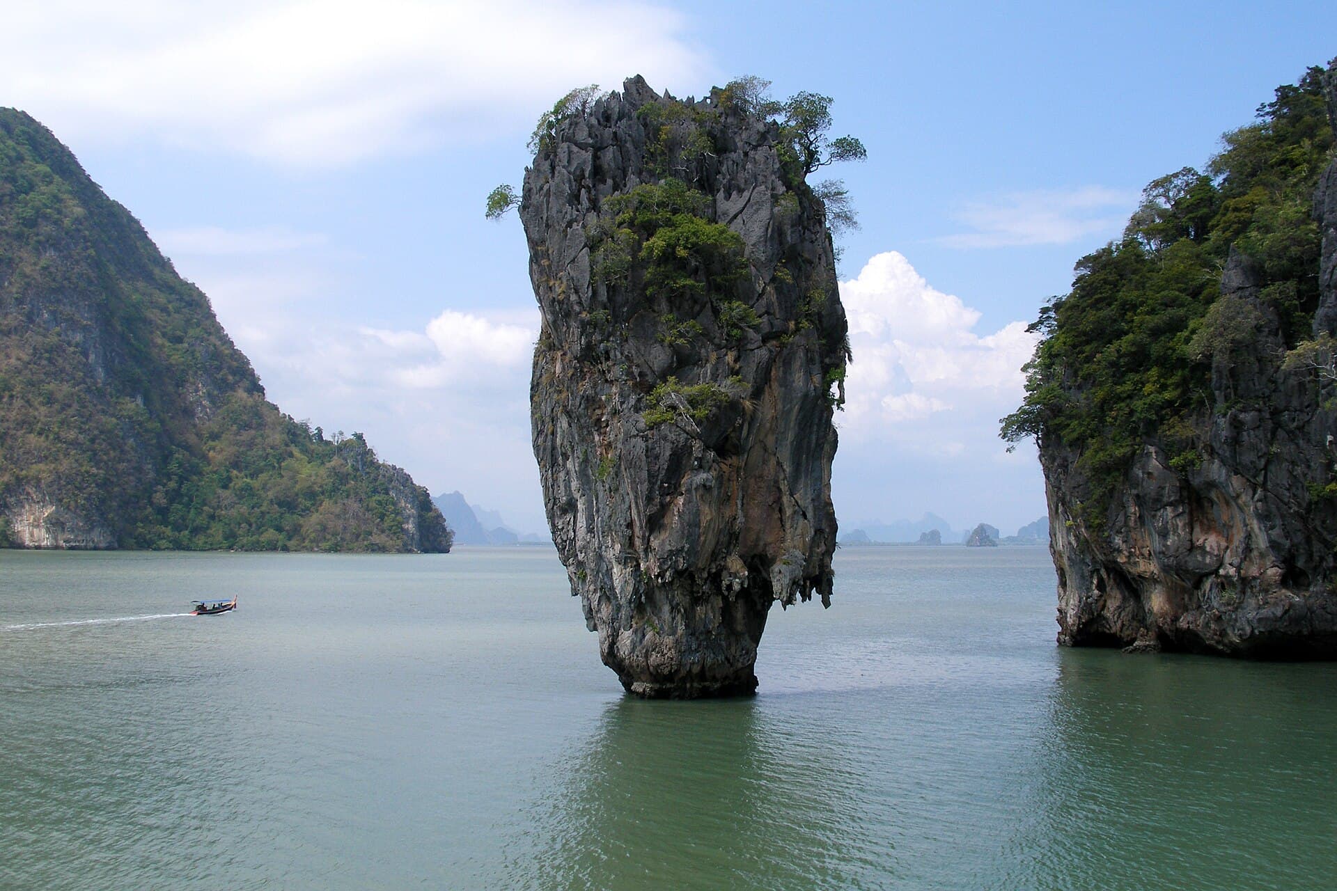 Ko Tapu, the top-heavy limestone needle rock known as James Bond Island, rising from Phang Nga Bay with a longtail boat passing