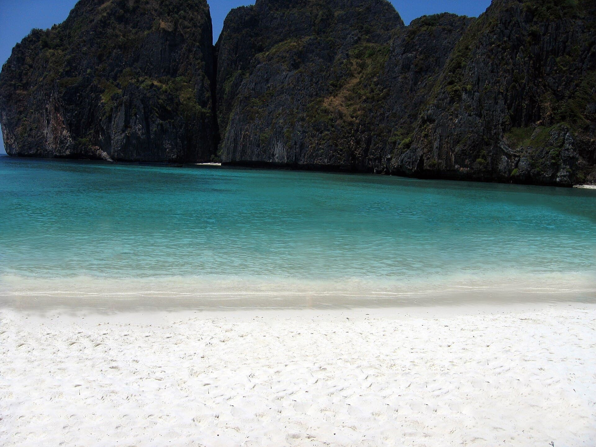 Maya Bay's turquoise water meeting a white-sand beach, framed by towering limestone cliffs