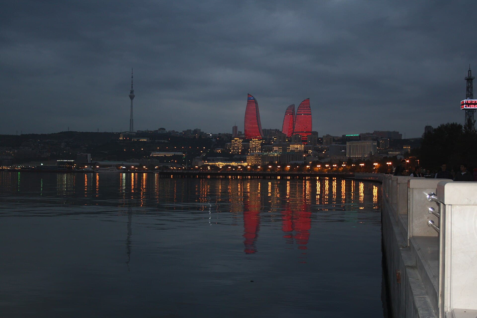 The three Flame Towers lit red at night, their glow reflected in the water along Baku Boulevard