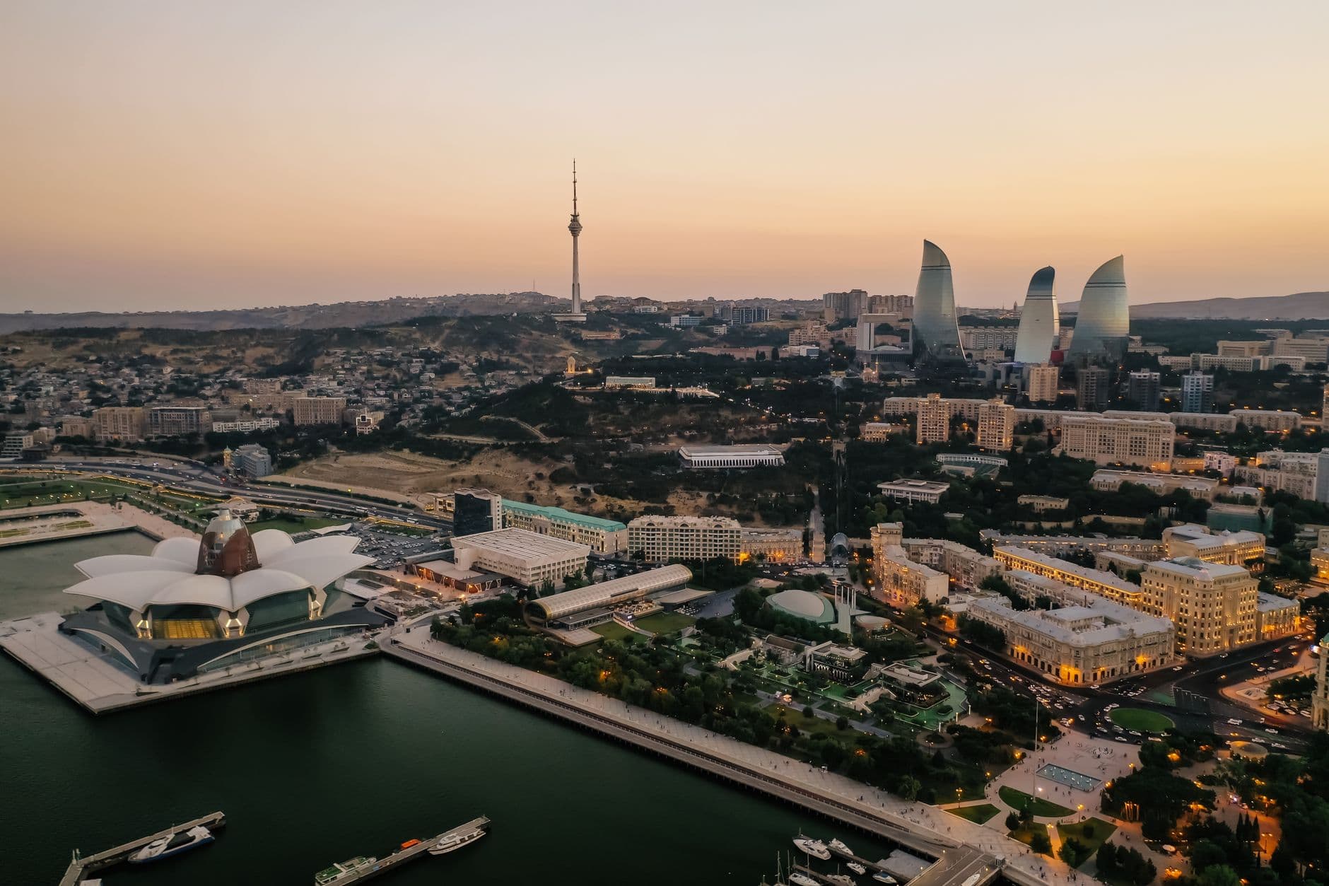 Aerial sunset view of Baku's skyline — the Flame Towers, TV tower and waterfront Crystal Hall on the Caspian shore