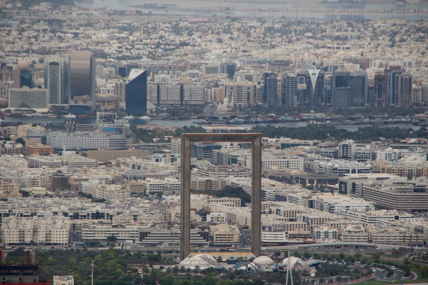 The golden rectangular Dubai Frame standing over the city skyline, Dubai Creek and Deira visible behind it