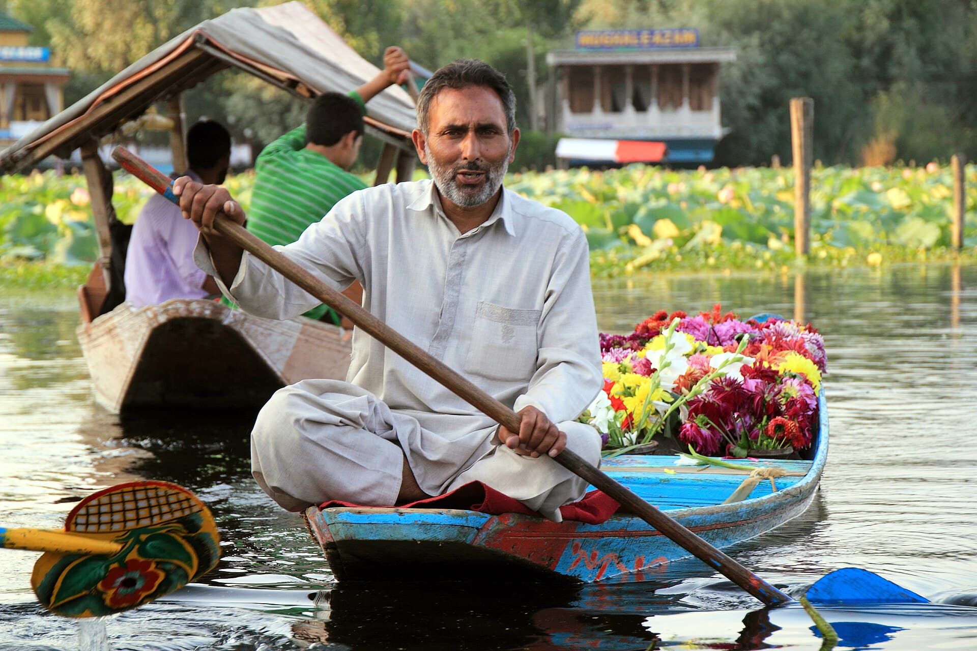 A flower-seller poling his boat laden with fresh blooms through Dal Lake's lotus pads at sunset