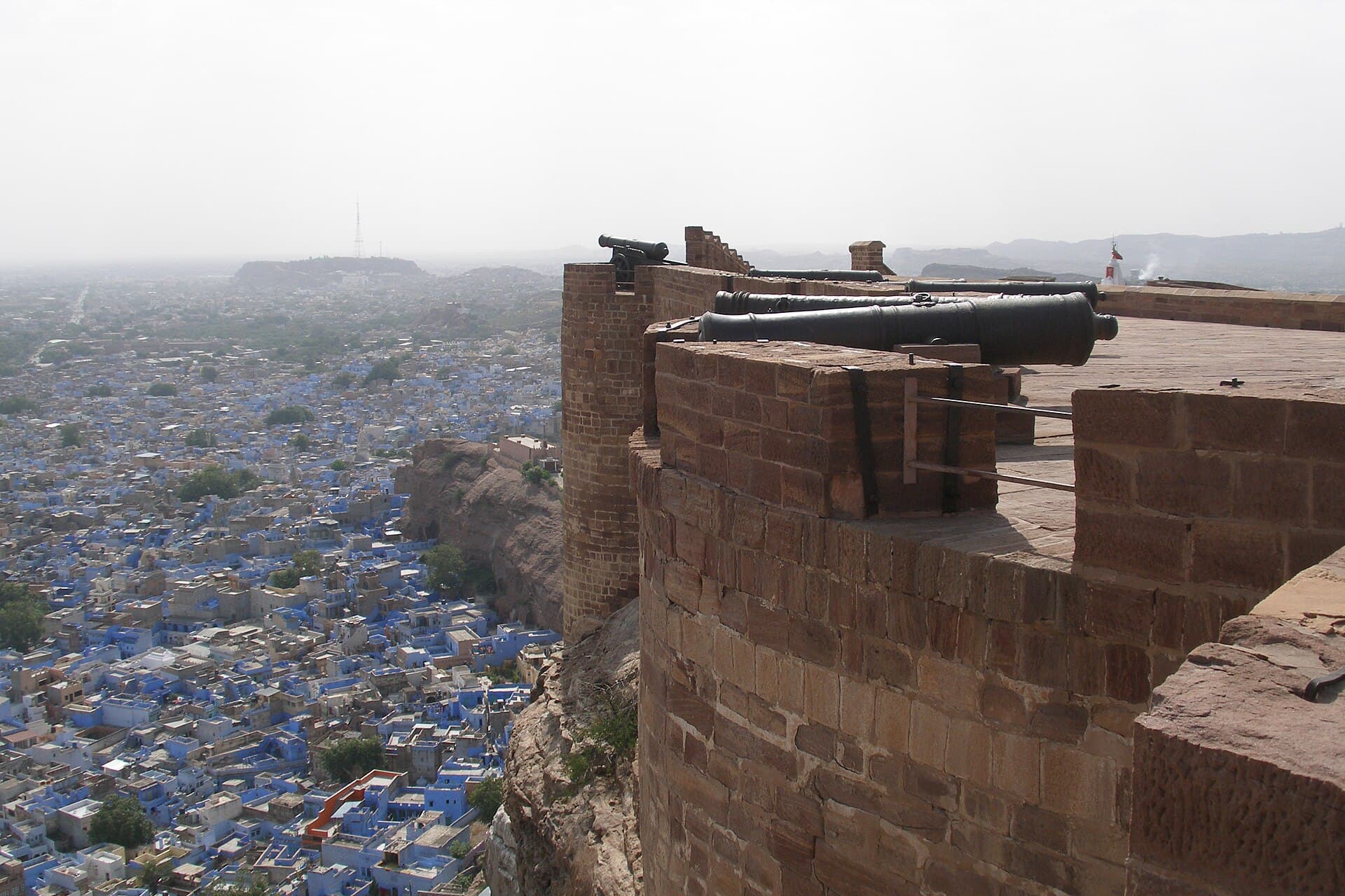 Cannons on Mehrangarh Fort's ramparts looking straight down over the indigo-washed houses of Jodhpur's Blue City