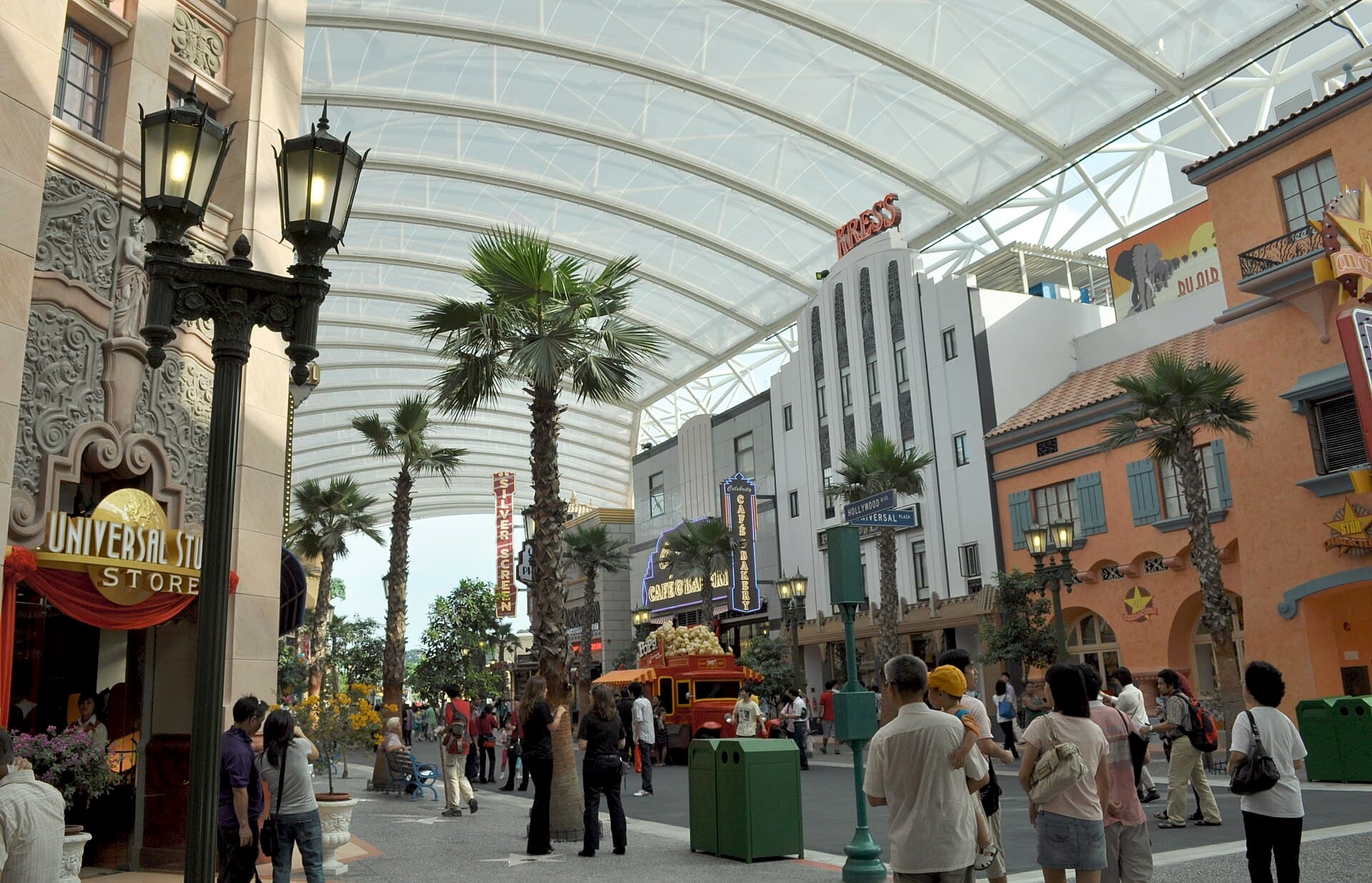 Hollywood Boulevard at Universal Studios Singapore, palm-lined under a vaulted glass canopy with visitors strolling